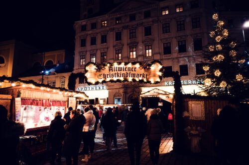 Visitors browsing vendor stands at Freyung Christmas market Vienna.