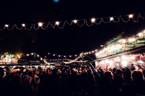 Visitors browsing Art Advent market stalls on Karlsplatz in front of Karlskirche (St. Charles Church).