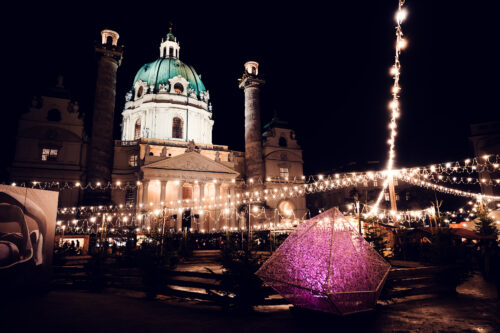 Illuminated Karlskirche (St. Charles Church) with Art Advent vendors on Karlsplatz.