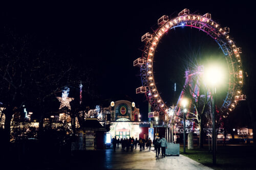 Wintermarkt Christmas market stalls at Riesenradplatz Vienna with Giant Ferris Wheel in background.