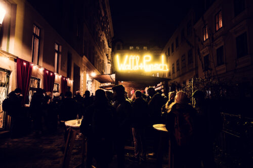 Traditional wooden market stalls at Spittelberg Christmas Market with Biedermeier architecture in background.