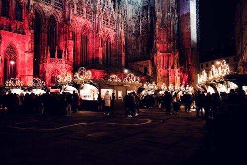 Traditional wooden market stalls at Stephansplatz Christmas Market with 12th-century cathedral facade behind.