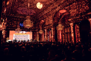 Wide view of the Strauss Hall during a concert with golden light projections.