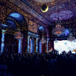 Blue-lit Strauss Hall with golden light effects during a concert evening.