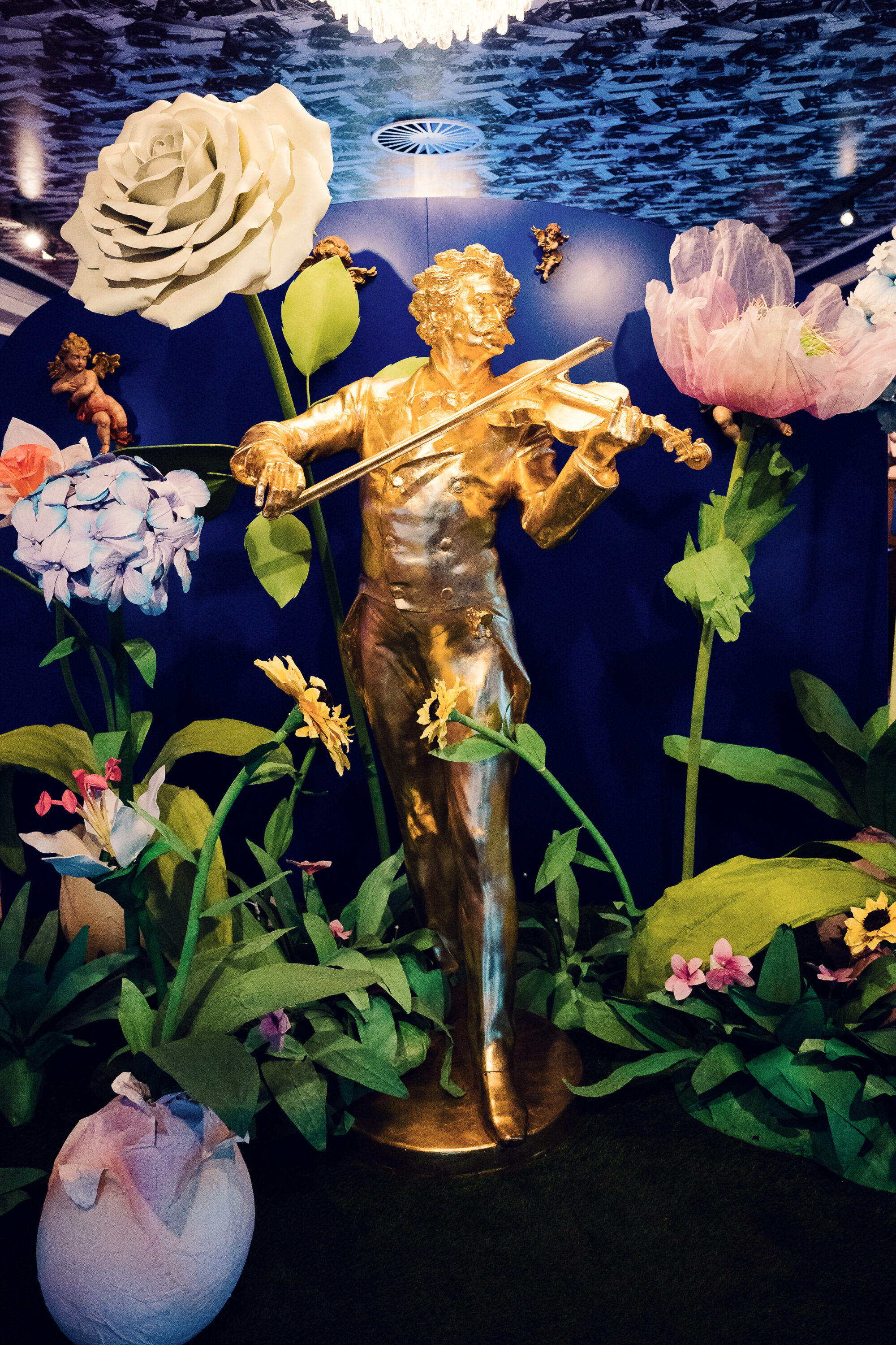 Close-up of the golden Johann Strauss statue with floral arrangement.
