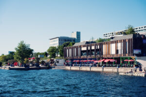 Wooden waterfront restaurant with red umbrellas along the Neue Donau at Pier 22.