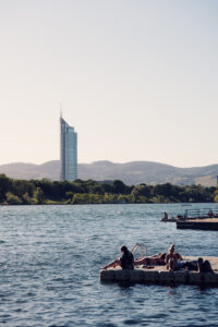 Sunbathers relaxing on a floating swim platform on the Neue Donau below the Millennium Tower.