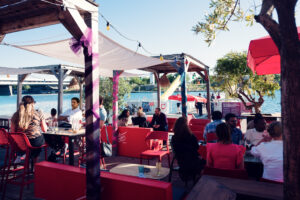 Lively Copa Beach terrace with red furniture and string lights by the water.