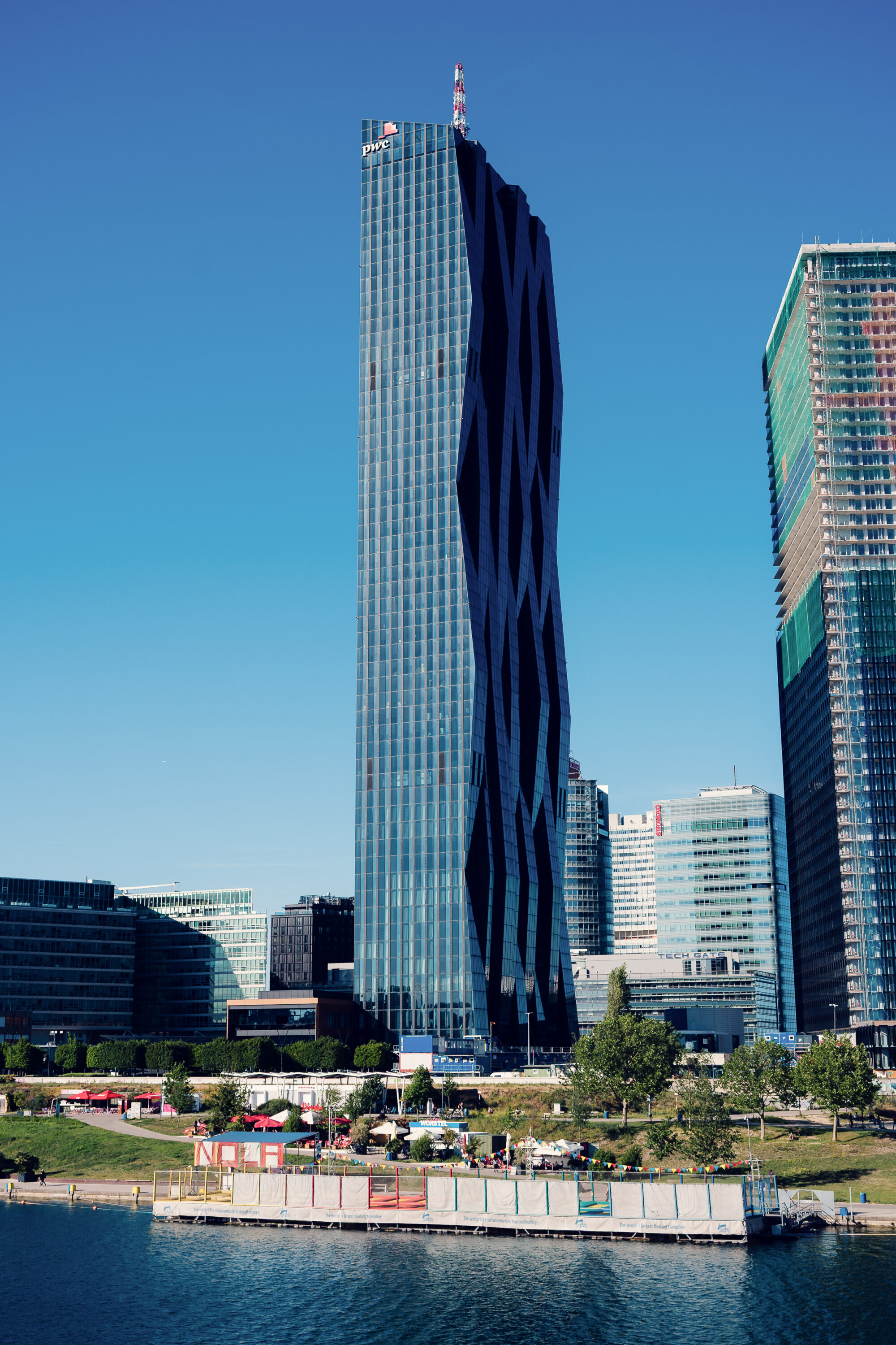 The curved DC Tower rising above Donau City beside the Neue Donau at Copa Beach.