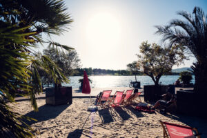 Red beach loungers on the sand beside a palm tree at Copa Beach.