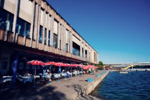 The Pier 22 building with red parasols and a waterside terrace beside Ponte Cagrana.