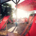 Red deck chairs and parasols on a sunlit Copa Beach terrace.