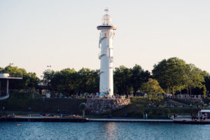 The white Copa Beach lighthouse on its stone base surrounded by trees.