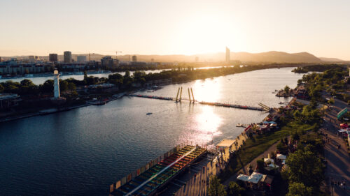 Aerial golden hour view over Copa Beach, the lighthouse and Ponte Cagrana on the Neue Donau.