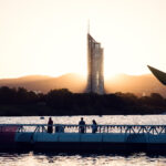 Visitantes en el puente flotante al atardecer, con el Millennium Tower más allá de Copa Beach.
