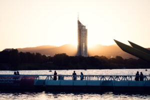 Visitors on the floating bridge at sunset with the Millennium Tower beyond Copa Beach.