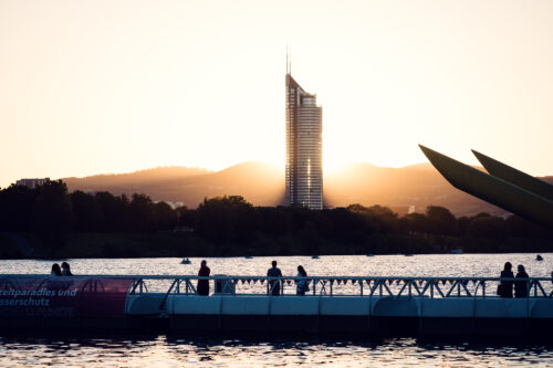 Visitors on the floating bridge at sunset with the Millennium Tower beyond Copa Beach.