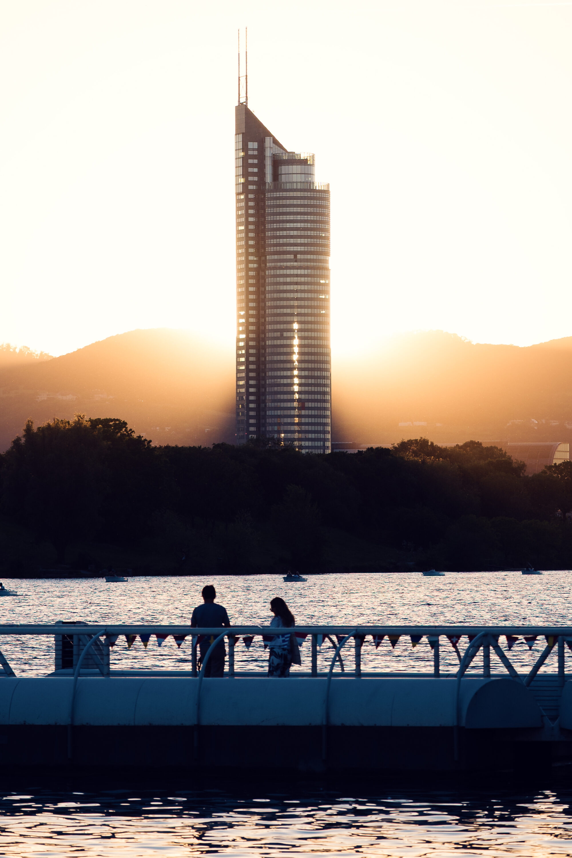 Silhouetted visitors on the Copa Beach bridge as the sun sets behind the Millennium Tower.