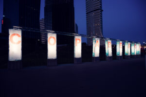 Illuminated Copa Beach letter columns glowing against the Donau City skyline at dusk.