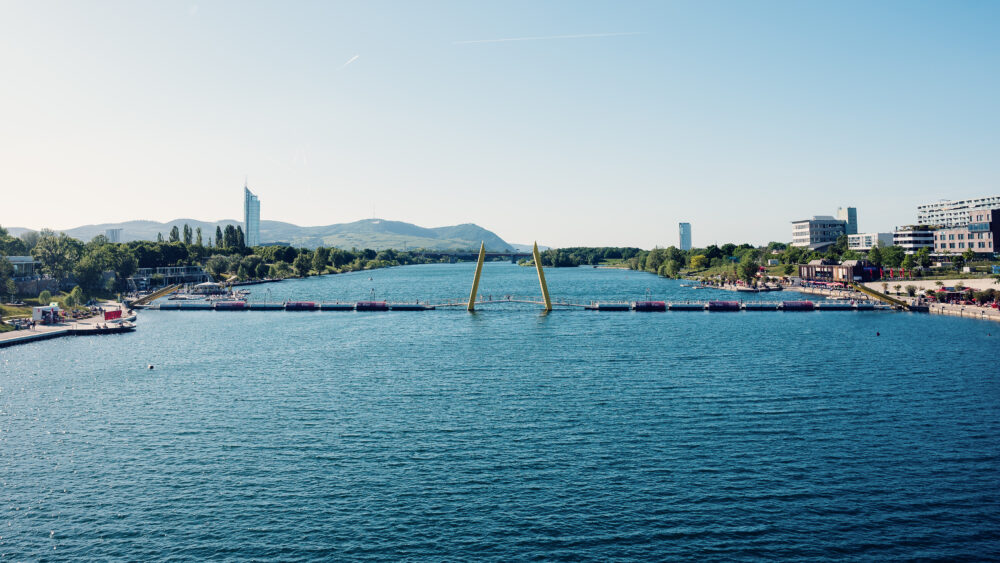 Calm Neue Donau stretching toward the Vienna Woods hills near Ponte Cagrana.