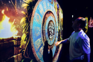 Mario interacting with a projected Maya calendar stone surrounded by fire effects.
