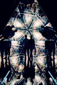 Adriana and Mario silhouette inside the mirrored pyramid room surrounded by golden geometric light patterns.