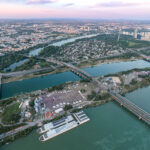 Aerial view of Donauinselfest on the Donauinsel at dusk, the festival ground between the Danube and the Neue Donau with Vienna's skyline behind